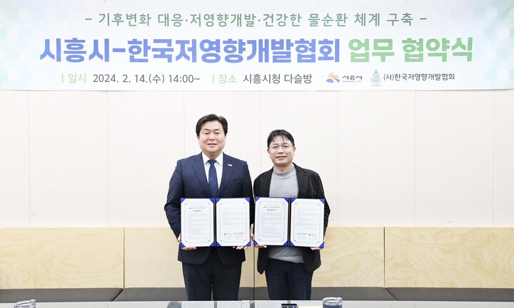 임병택 시흥시장과 최경영 한국저영향개발협회장이 협약서를 들고 기념사진을 찍고 있다.